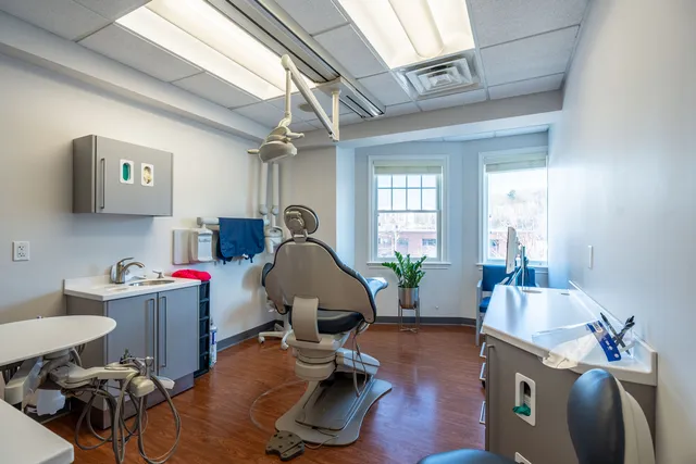 Modern dental treatment room with freshly painted white walls, gray cabinetry, hardwood floors, and natural light — commercial interior painting by Paint Pros MA.