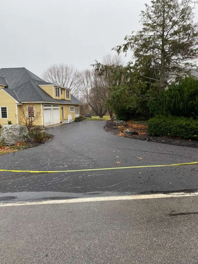 Crime scene tape surrounds a wet driveway leading to a house