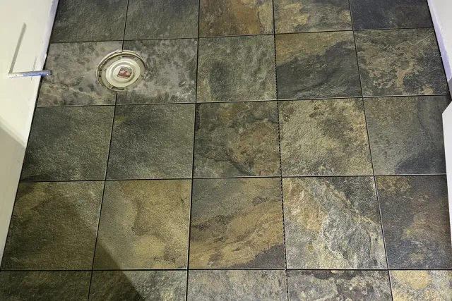 Multicolor slate-look porcelain floor with a clean hardwood transition, installed by Dmtilellc