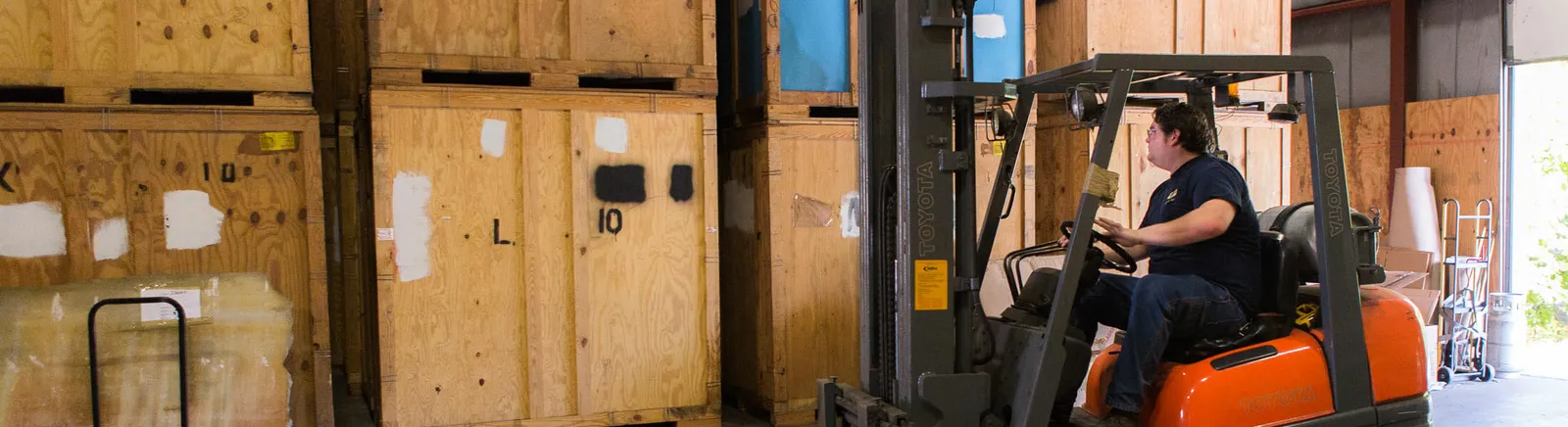 Forklift moving palletized storage vaults in the company warehouse
