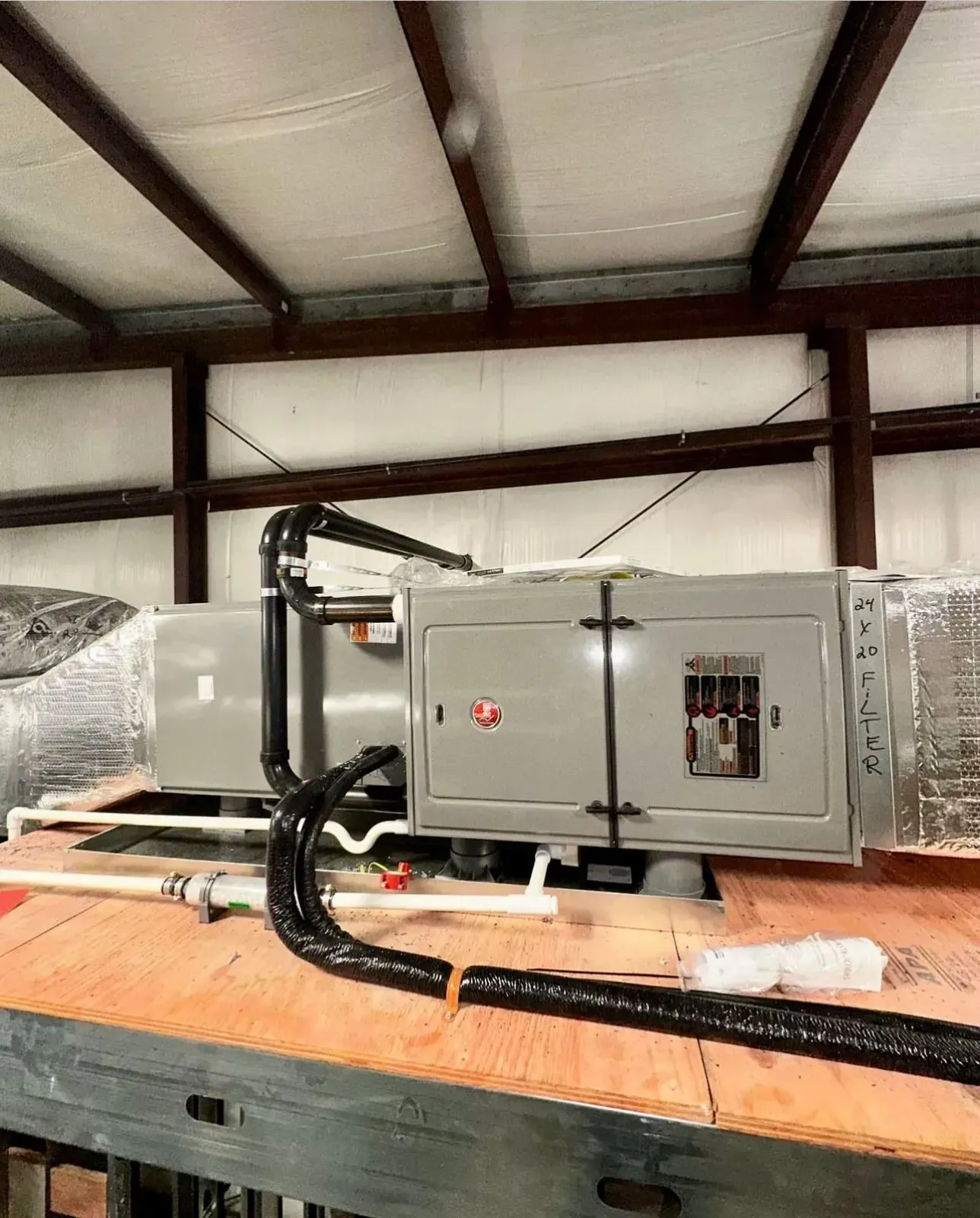 Large HVAC unit wrapped in plastic on a wooden pallet inside a metal warehouse