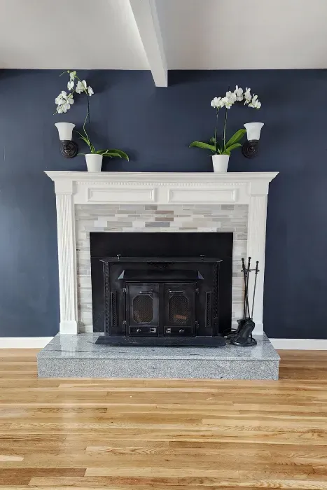 Living room fireplace wall painted navy blue with white mantle trim and hardwood floor by Link Services Pro in Auburn, MA