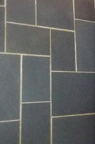 Accessible beige tiled shower with bench, grab bar, multiple shower heads and fixtures.