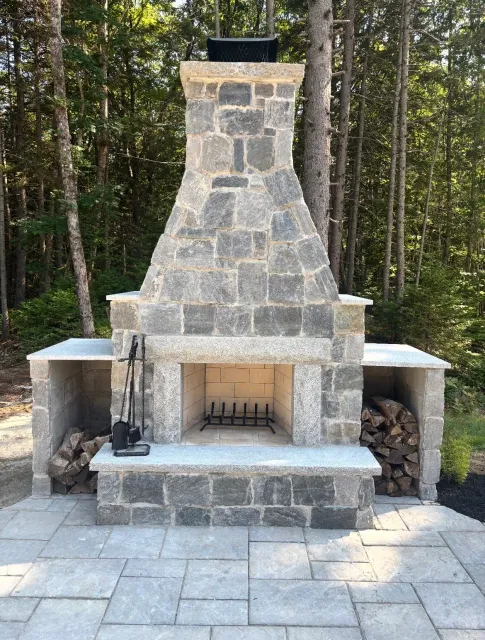 Custom outdoor wood burning stone fireplace installed in Southern Maine