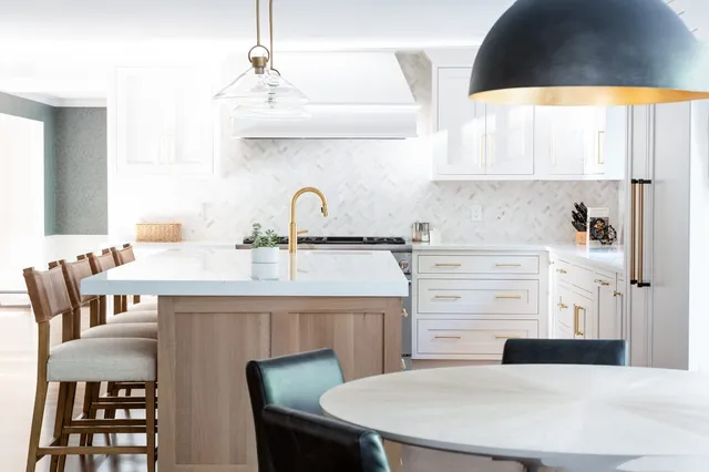 Rosewood Court kitchen — close-up of white oak island, brass faucet, and marble herringbone backsplash