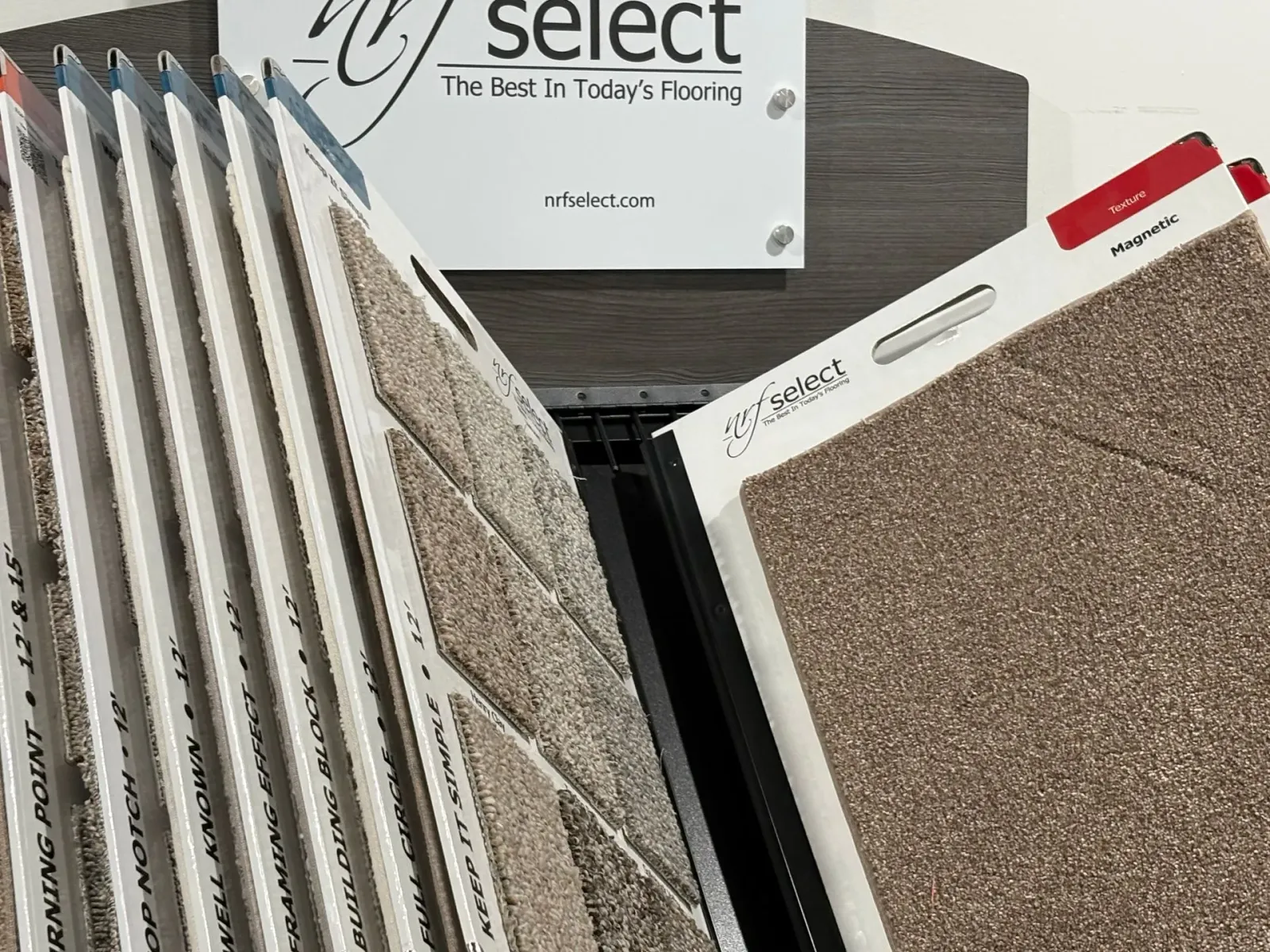 Assorted flooring and carpet samples displayed in a showroom, with textured neutral-toned swatches in open books.
