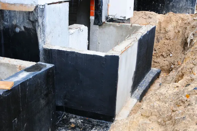Foundation walls under construction, coated with black sealant