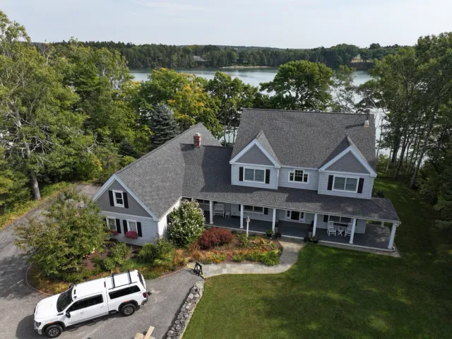 Aerial view of a large house, driveway with truck, and lake