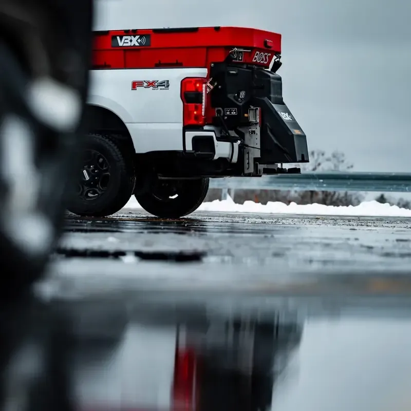Pickup truck fitted with a BOSS plow and VBX salt spreader on a cleared winter lot