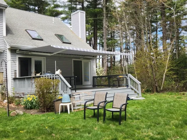 Backyard with patio deck, outdoor furniture, and garden, surrounded by trees.