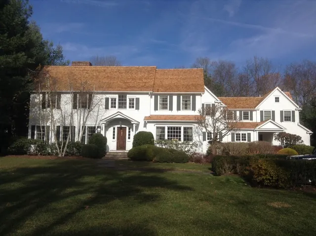 Traditional white residence with a warm cedar roof