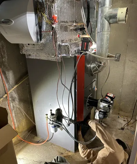 Exposed HVAC/utility equipment with ducts, pipes, wiring, and a furnace in a basement or mechanical room.