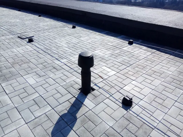 Flat roof with a brick-like pattern, vent pipe, and various other fixtures.