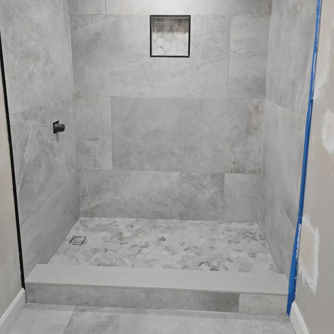 Large-format gray porcelain shower with hexagon mosaic floor and niche by Link Services Pro in Millbury, MA