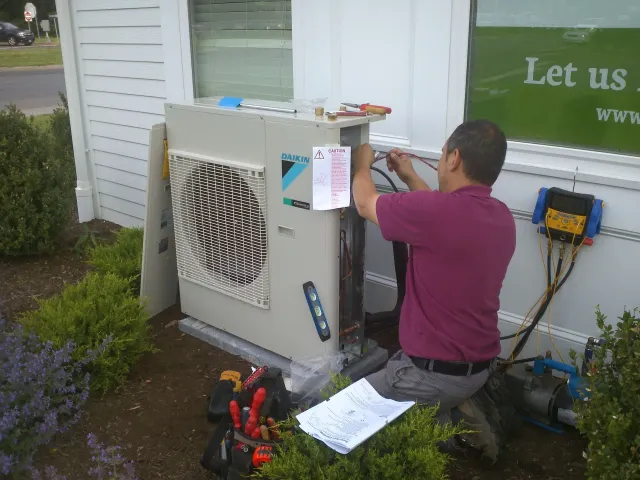 A man is working on an air conditioner outside of a building