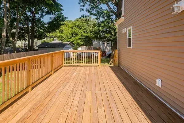 A large wooden deck with a railing in front of a house