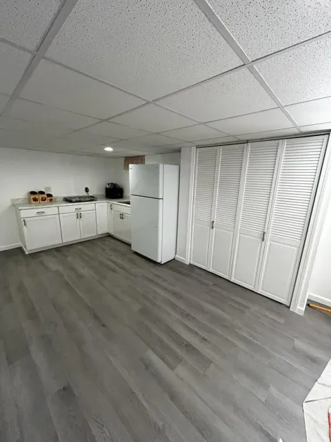 Basement room with newly installed gray vinyl plank flooring and white cabinetry
