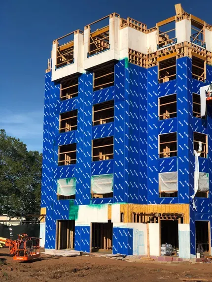 A large building is being built with a blue covering