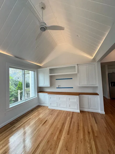 An empty living room with hardwood floors and a ceiling fan