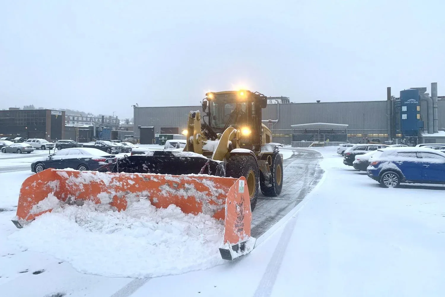 A large snow plow removes snow from a commercial property parking lot after a snow storm in Massachusetts.