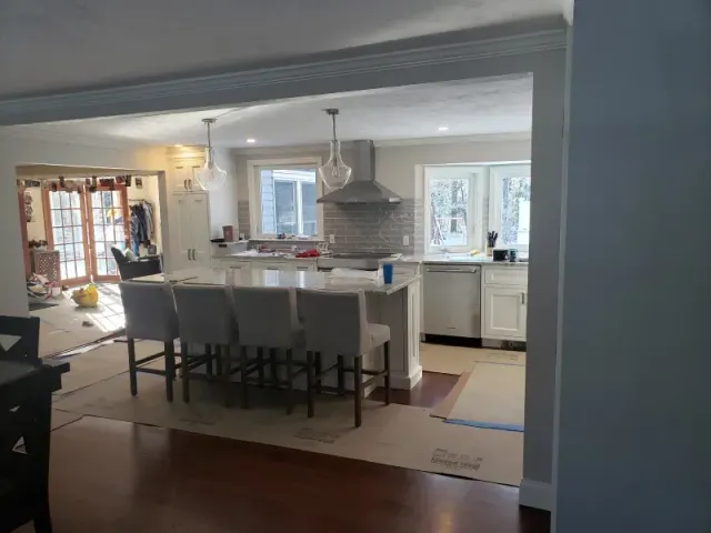 Kitchen renovation: open layout with island, bar stools, and white cabinetry.