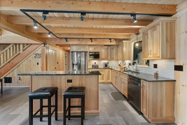 A kitchen in a log cabin with wooden cabinets and stools.