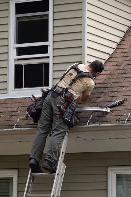 Professional contractor on ladder installing gutter system on residential home exterior