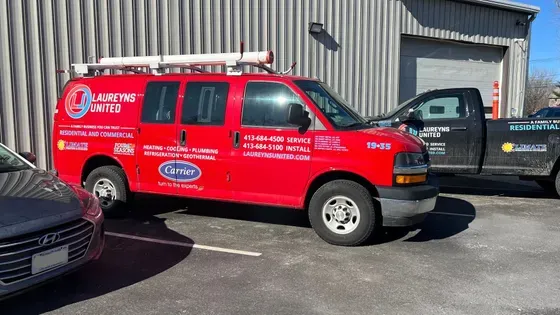 A red van is parked in a parking lot next to a black truck.