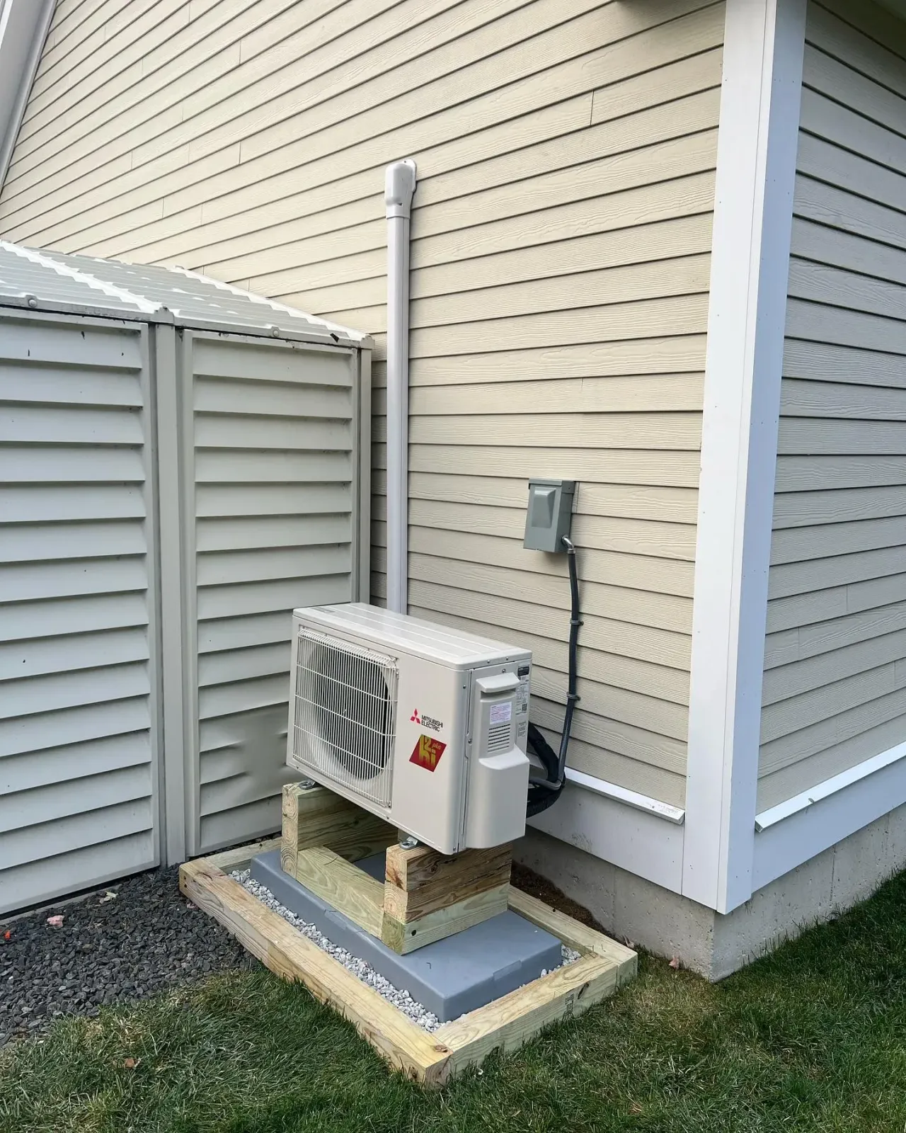 A small air conditioner is sitting on the side of a house.