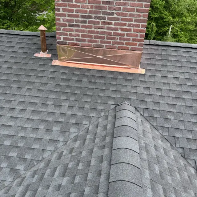 Brick chimney with copper flashing on a new grey shingle roof