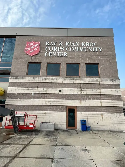Exterior of the Salvation Army Ray & Joan Kroc Corps Community Center building, featuring tan brick and a red logo.