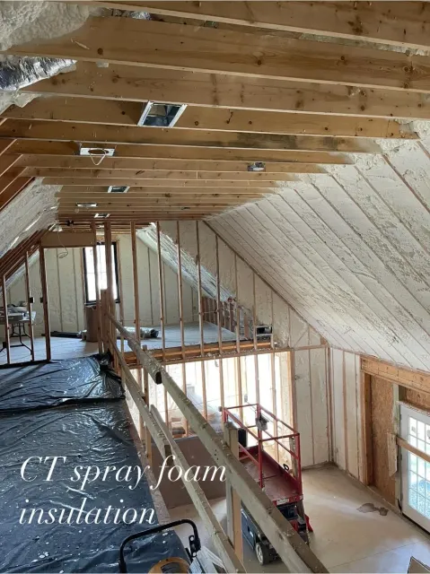 Interior view of a building under construction, spray foam insulation applied to walls and ceiling, open framing.
