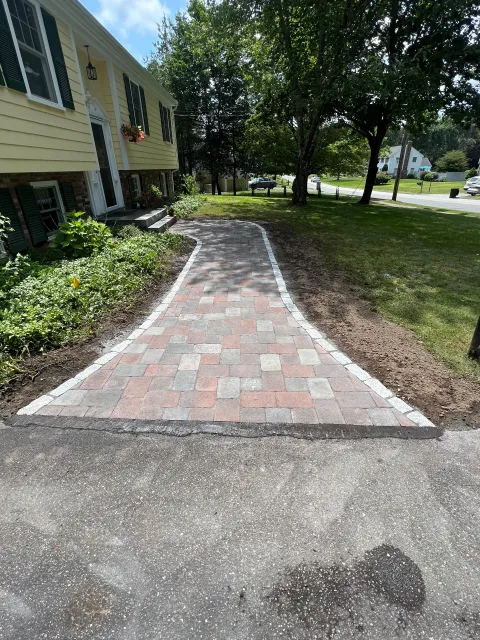 A brick walkway is being built in front of a house.