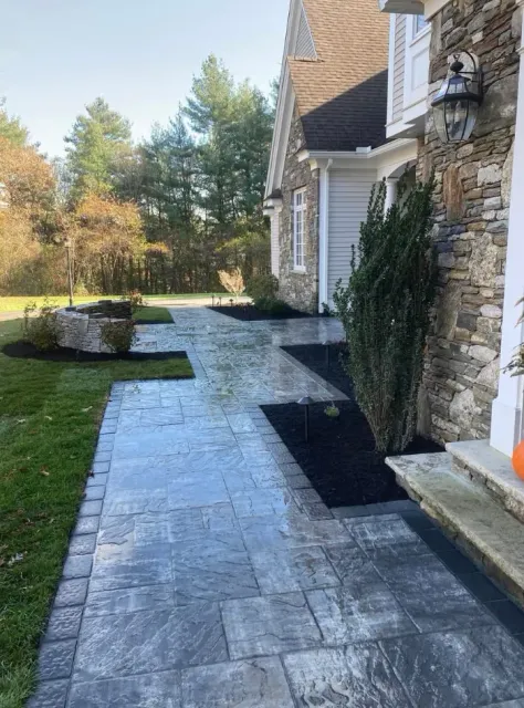 Stone walkway leading to a house with manicured landscaping and a stone facade.