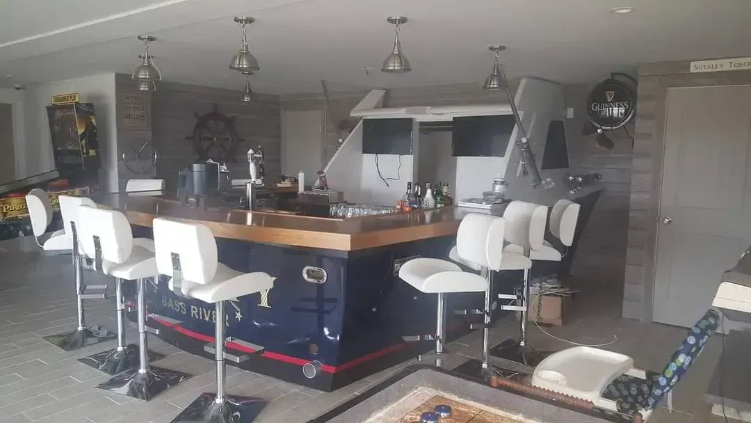 A large room with a bar and stools in it.