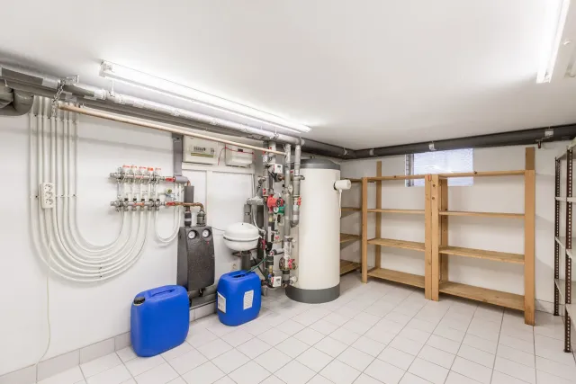 A basement with a water heater , sink , and shelves.