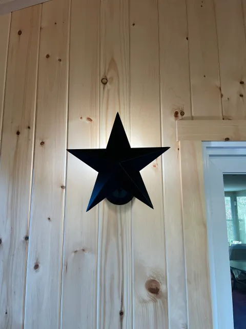 A black star is hanging on a wooden wall