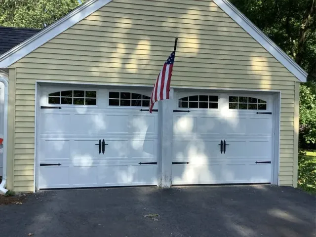 A garage with two white doors and an american flag