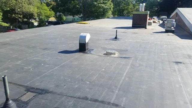 A roof with a chimney on it and trees in the background.