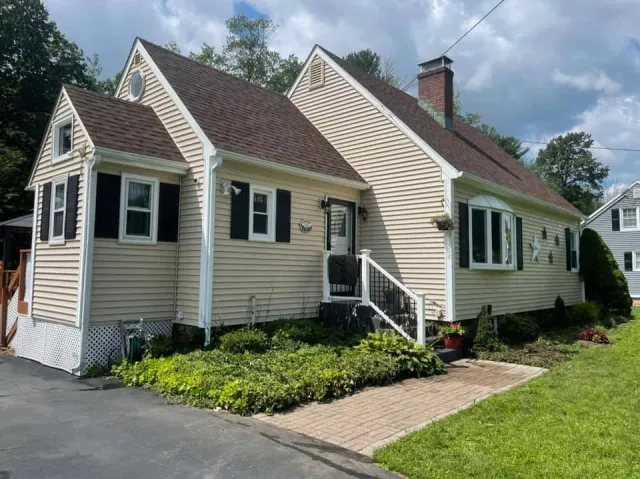 A house with a brown roof and black shutters is for sale.