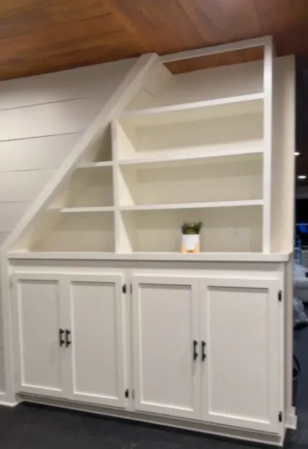 White built-in hutch with open shelves and cabinet doors in a room with a slanted ceiling.