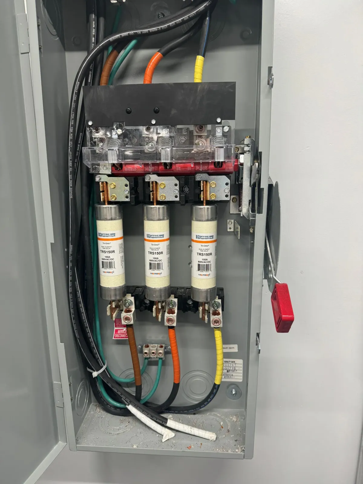 Electrical panel with three fuses, wires, and a red safety lock.