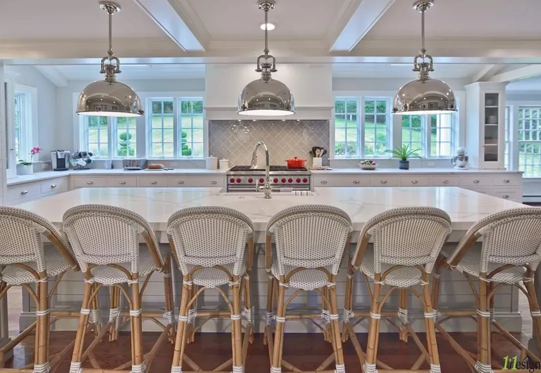 Kitchen island lit by three polished pendant fixtures with recessed lighting across the ceiling