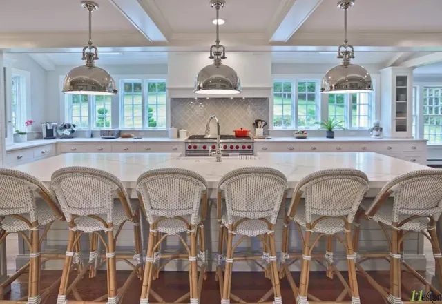 Kitchen island lit by three polished pendant fixtures with recessed lighting across the ceiling