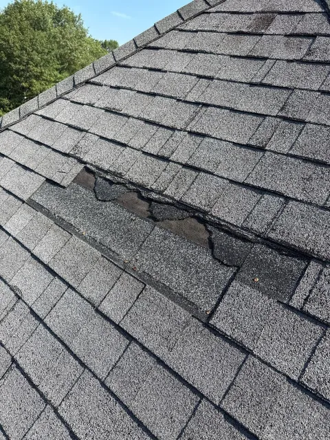 Close-up of a shingled roof with a noticeable crack in one of the shingles