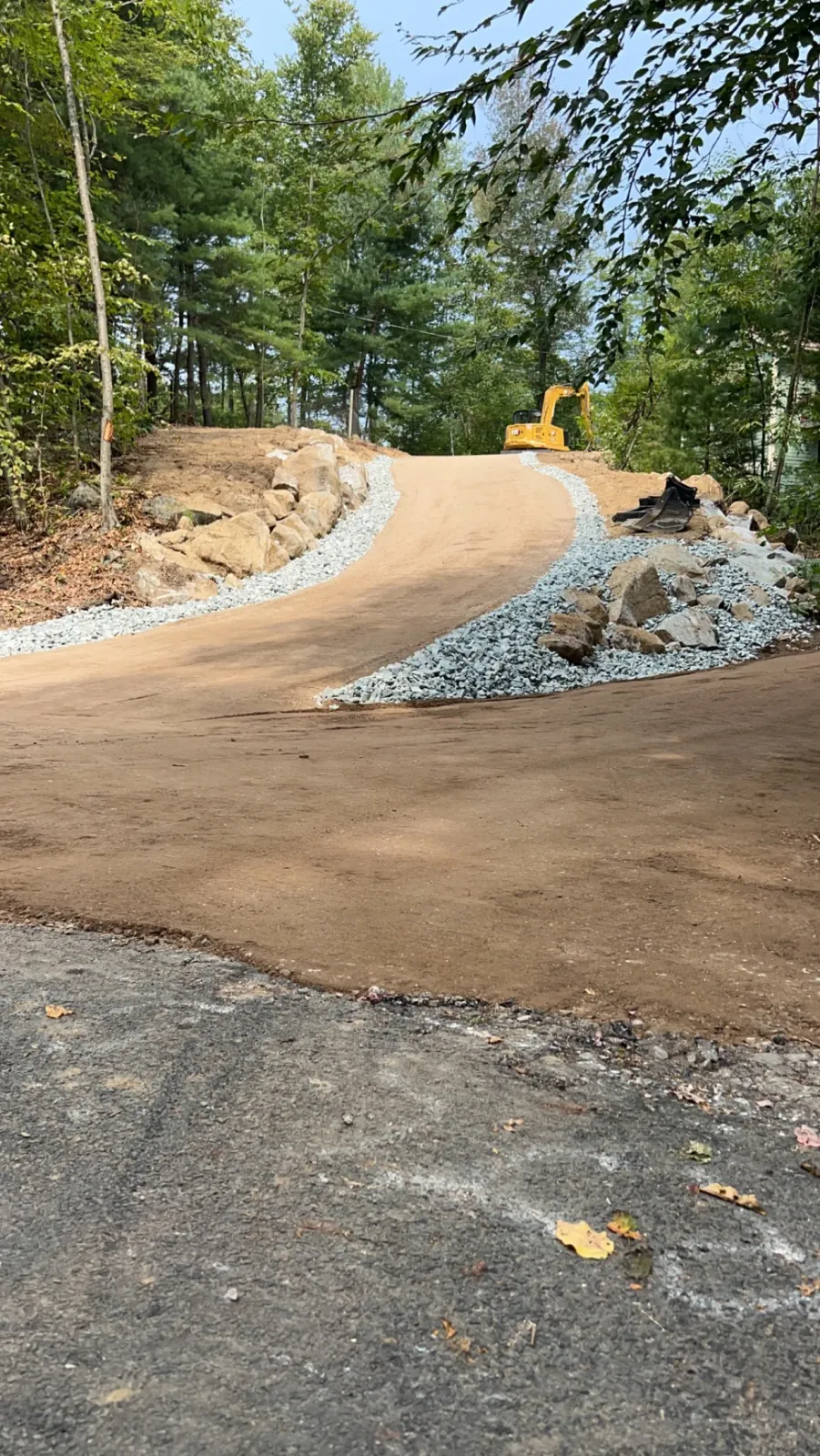 New crushed stone driveway cut through wooded terrain with stone edging, Hampden MA