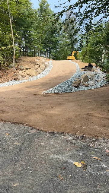 New crushed stone driveway cut through wooded terrain with stone edging, Hampden MA