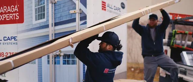 Two installers are loading a truck with a garage door.