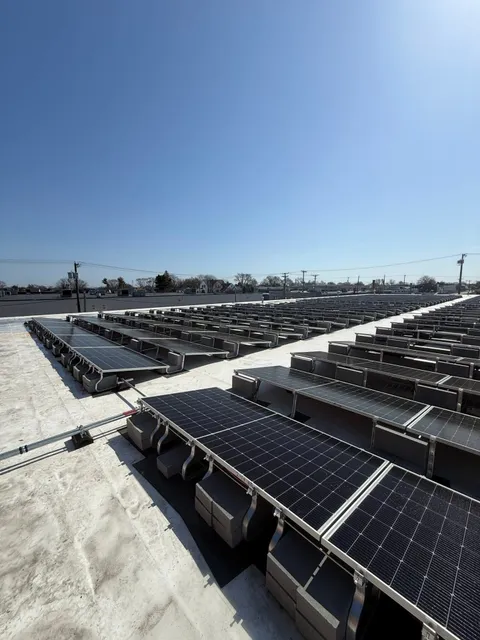 Rows of solar panels installed on a white flat commercial roof on a clear day