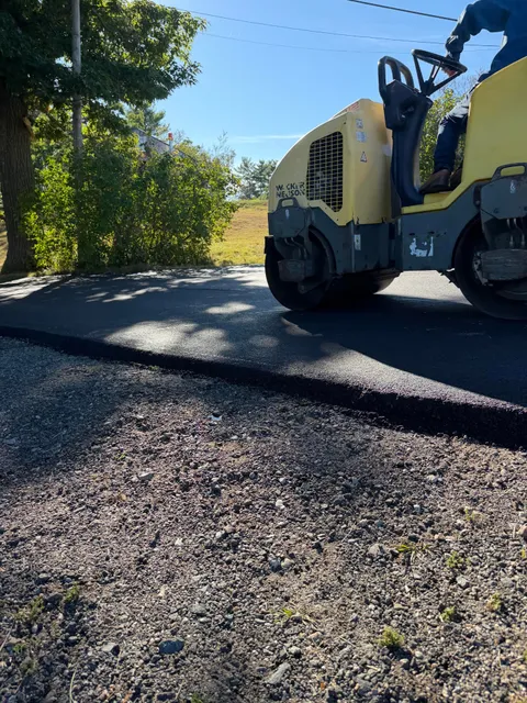 Roller compacting the fresh edge of a new asphalt driveway